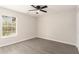 An empty bedroom with gray hardwood flooring, a ceiling fan, board and batten, and a window at 8044 Old London Rd, North Charleston, SC 29406