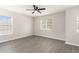 An empty bedroom with gray hardwood flooring, two windows, board and batten, and a ceiling fan at 8044 Old London Rd, North Charleston, SC 29406