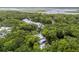 Aerial view of several homes with metal roofs surrounded by dense forest, with a glimpse of a waterway in the distance at 8187 Jack Island Dr, Johns Island, SC 29455