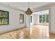 Spacious living room with hardwood floors, a modern chandelier, and large windows with a wooded view at 8187 Jack Island Dr, Johns Island, SC 29455
