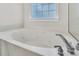 A large white soaking tub sits below a window, providing a relaxing bath experience at 8618 Woodland Walk, North Charleston, SC 29420