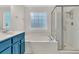 A large tub and shower sits beside a blue vanity in this bright bathroom at 8618 Woodland Walk, North Charleston, SC 29420