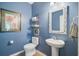 Cozy powder room featuring a pedestal sink, decorative mirror, and blue painted walls at 9808 Wooden Pestle Way, Ladson, SC 29456