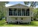 A view of the home's back exterior featuring a raised screened porch with dual ceiling fans at 1014 E Cooper Ave, Folly Beach, SC 29439