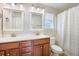 Bright bathroom with dual sinks, cherry vanity, shower and tub with patterned shower curtain at 105 Lovette Ct, Goose Creek, SC 29445