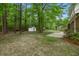 View of the backyard featuring mature trees, storage shed, and a concrete patio at 105 Spring St, Summerville, SC 29485