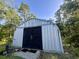 Exterior view of metal barn with black wooden doors in wooded setting at 1173 Penny Creek Dr, Ruffin, SC 29475