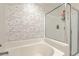 Close-up of tub and glass-enclosed shower in bathroom with brick patterned wall at 1723 Brittlebush Ln, Johns Island, SC 29455