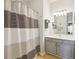 Neutral bathroom with striped shower curtain, vanity, and ample lighting at 2329 Tall Sail Dr # 704D, Charleston, SC 29414