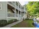 Exterior view of a charming, light-green home with multiple levels of covered, white-columned porches overlooking a tranquil stream at 2329 Tall Sail Dr # 704D, Charleston, SC 29414