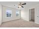 Well-lit bedroom with neutral walls, carpet, ceiling fan, and view of neighborhood through two large windows at 316 Beachgrass Ln, Summerville, SC 29486