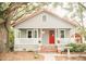 Charming single-story home featuring a cozy front porch, red door, and mature trees at 317 Bay St, Walterboro, SC 29488