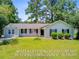Charming single-story home features a well-manicured lawn and a classic design with black shutters and natural landscaping at 405 Amberjack Way, Summerville, SC 29485
