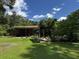 Expansive backyard with a brick home, covered patio, mature trees, and a shed at 409 Azalea Dr, Walterboro, SC 29488
