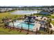 Aerial view of community pool with palm trees, lounge chairs, and amenities by a lake at 658 Yellow Leaf Ln, Summerville, SC 29486