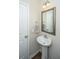Cozy half-bathroom featuring a pedestal sink, framed mirror, and convenient access to an adjacent door at 72 Crossandra Ave, Summerville, SC 29483