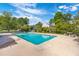 Community pool area with clear blue water surrounded by patio, trees, and a lake at 7814 Nummie Ct, North Charleston, SC 29418