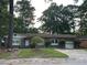 Single-story brick home with a well-maintained lawn and mature trees providing shade at 8334 Witsell St, North Charleston, SC 29406