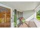 A view of the charming front porch with wicker seating, a potted tree and a decorative door at 115 W Park Ln, Summerville, SC 29486