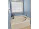 A pristine white bathtub is bathed in natural light from a window with blinds, creating a relaxing atmosphere at 116 Marshside Dr, Summerville, SC 29485