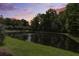 Scenic pond view surrounded by lush trees and landscaping at sunset at 136 Heart Pine Cir, Summerville, SC 29485