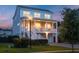 Charming two-story coastal home with a welcoming front porch and a warm glow at dusk at 1464 Stratton Pl, Mount Pleasant, SC 29466