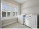 Well-lit laundry room with a window, tile floor, overhead shelving, and modern washer and dryer at 1464 Stratton Pl, Mount Pleasant, SC 29466