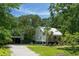 Well-maintained home with a metal roof, complemented by a detached garage, lush landscaping, and serene natural surroundings at 1515 N Lakeshore Dr, Mount Pleasant, SC 29466