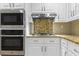 Modern kitchen features stainless steel microwave, oven and range hood above granite countertops and white cabinets at 1551 Hutton Pl, Charleston, SC 29407