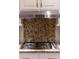Close up of a gas range with stainless steel range hood and decorative backsplash at 1551 Hutton Pl, Charleston, SC 29407