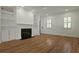 Living room with hardwood floors, a fireplace with custom shelving, and an abundance of natural light streaming through shuttered windows at 2258 Arthur Gaillard Ln, Charleston, SC 29414