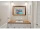 Bathroom vanity with a wood-look countertop, white cabinets, a framed mirror, and globe lighting at 2425 Vistavia Rd, North Charleston, SC 29406