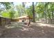 A spacious backyard with mature trees features a fire pit and wooden chairs, perfect for outdoor enjoyment at 2831 Chicopee Dr, North Charleston, SC 29420