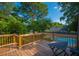 Wooden deck with a dark table provides a serene spot overlooking a lush backyard and sparkling pool, perfect for relaxation at 406 S Gum St, Summerville, SC 29483