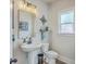 Cozy powder room featuring a pedestal sink, decorative mirror, and window with patterned glass for privacy at 4314 Cotton Flat Rd, Summerville, SC 29485