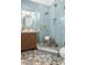 A modern bathroom with blue tile, glass shower with a bench, river rock floor, and a wood vanity with gold fixtures at 441 Elfes Field Ln, Charleston, SC 29492