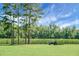 Expansive green field with a tractor, framed by tall trees and blue skies, perfect for outdoor activities at 4428 Maple Ridge Rd, Walterboro, SC 29488