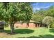 Charming brick home featuring a covered porch, surrounded by lush greenery and mature trees on a well-maintained lawn at 4428 Maple Ridge Rd, Walterboro, SC 29488