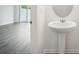 Bathroom featuring a pedestal sink, round mirror, and plank flooring extending from the adjacent room at 493 Colchester Court Ct, Moncks Corner, SC 29461