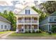 Charming two-story home features a brick facade and double balconies with lush landscaping at 5110 Hyde Park Village Ln, North Charleston, SC 29405