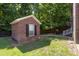 Brick shed in backyard with a single window, side door, and landscaping at 5110 Hyde Park Village Ln, North Charleston, SC 29405