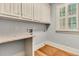 Functional laundry room featuring white cabinets, granite countertop, window with shutters, and hardwood floors at 512 Whilden St, Mount Pleasant, SC 29464