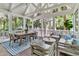 A relaxing screened-in porch features stylish furnishings, a dining table, and serene views of the surrounding lush greenery at 512 Whilden St, Mount Pleasant, SC 29464