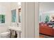 Elegant bathroom with a pedestal sink, stylish mirror, and a glimpse into the living room with an orange sofa at 6 Sayle Rd, Charleston, SC 29407