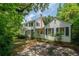White two-story home with black shutters and brick driveway surrounded by mature trees at 6 Sayle Rd, Charleston, SC 29407