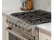 Close-up of a stainless steel stove with silver knobs and black grates on a white marble countertop at 6 Sayle Rd, Charleston, SC 29407