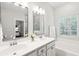 Bright bathroom with a double sink vanity, large mirrors, and a soaking tub under a window at 708 Lawton Harbor Dr, Charleston, SC 29412