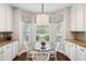Bright breakfast nook with a glass table, white chairs, and a bay window with white cabinets and granite counters at 708 Lawton Harbor Dr, Charleston, SC 29412