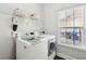 Well-lit laundry room with modern washer and dryer, plus storage shelf and window at 708 Lawton Harbor Dr, Charleston, SC 29412