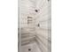 Close-up of a walk-in shower with gray and white tiling, a niche, and a hexagon tiled floor at 708 Lawton Harbor Dr, Charleston, SC 29412